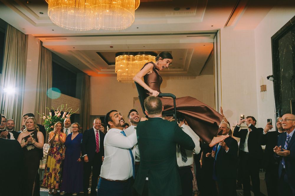 Wedding guests dance and celebrate on a dimly lit dance floor during an evening reception.