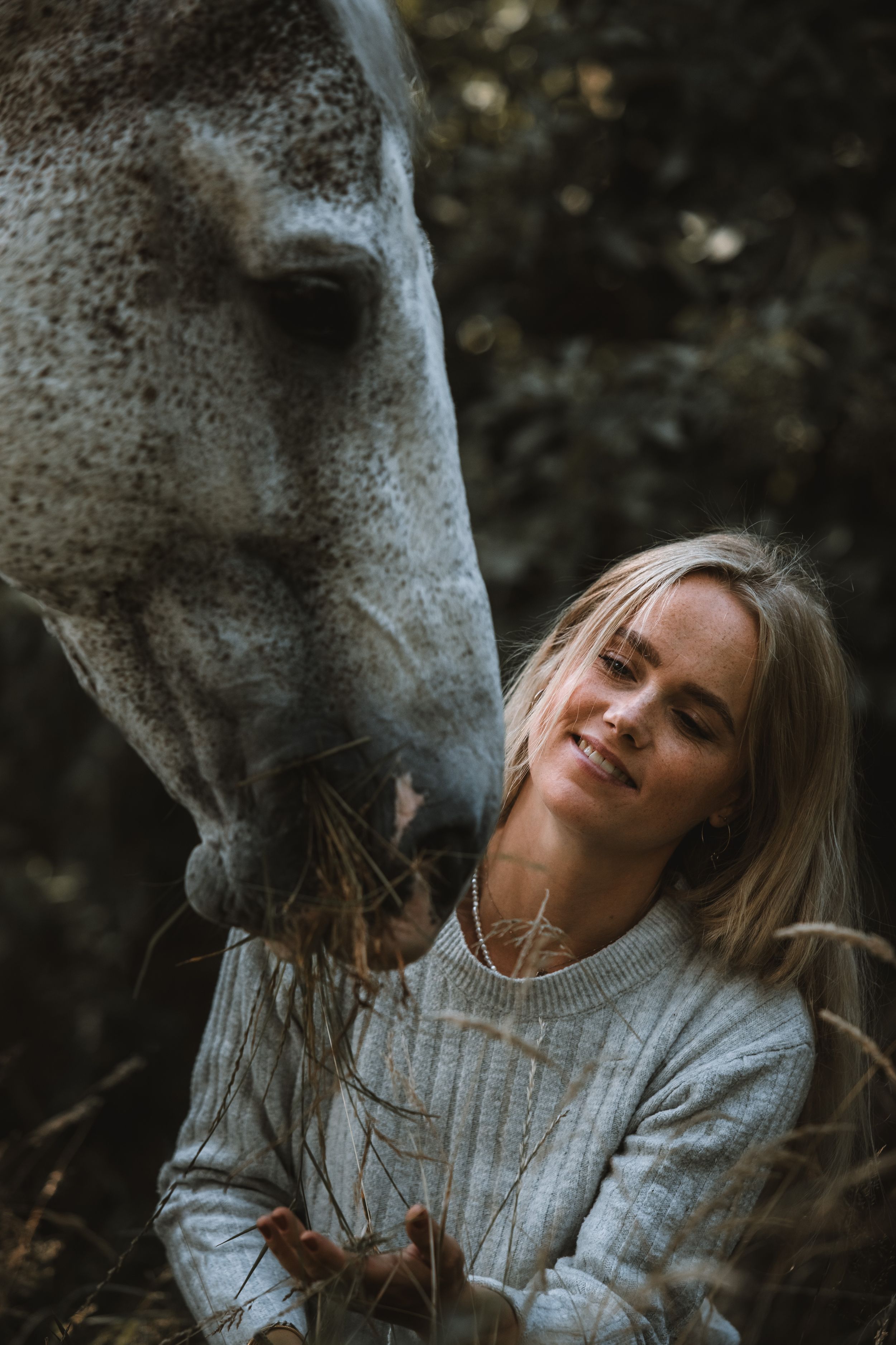 Nærbillede af kvinde med hvid hest fotograferet i naturen