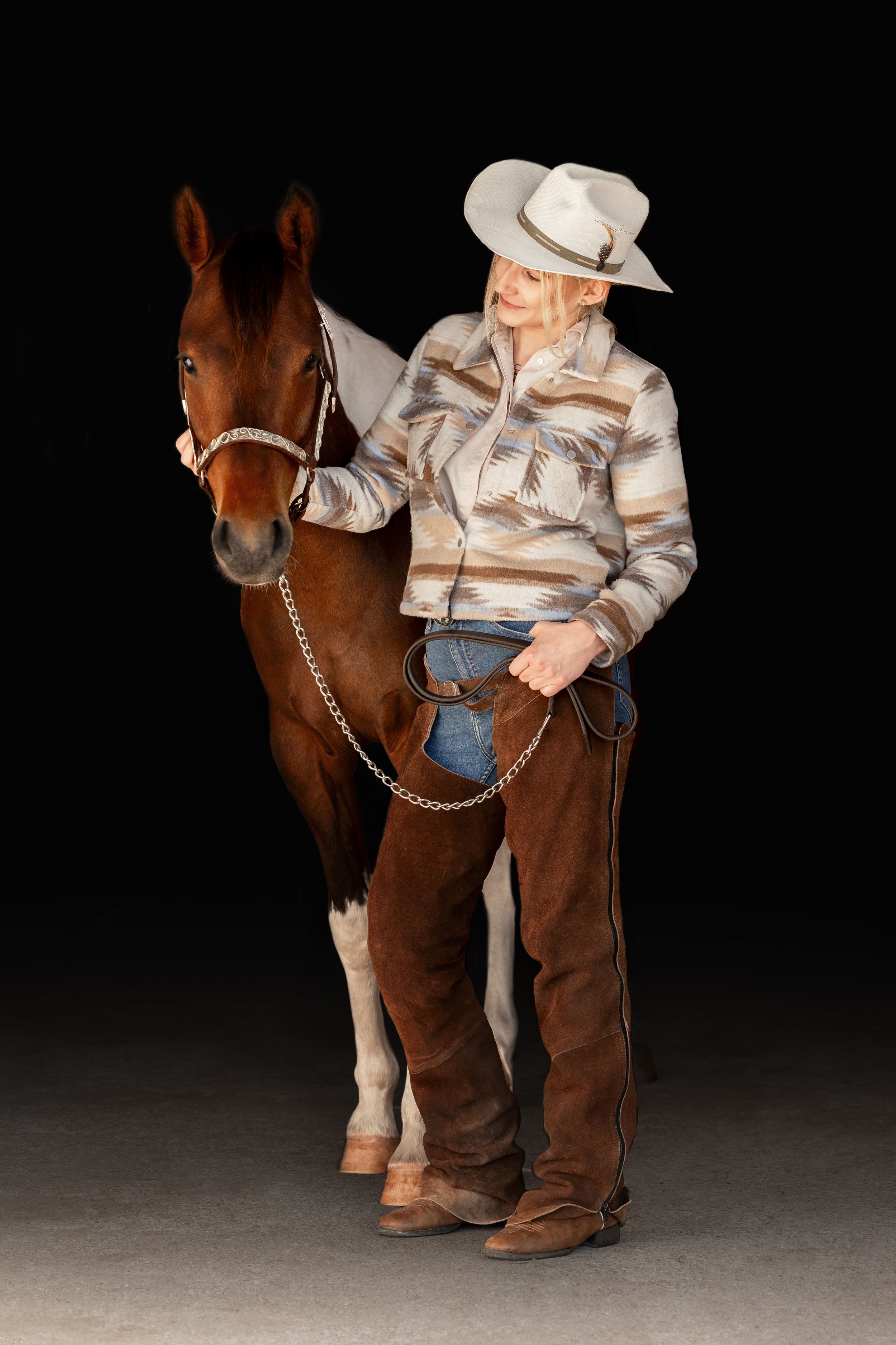 Westernrytter med paint hest foran sort baggrund