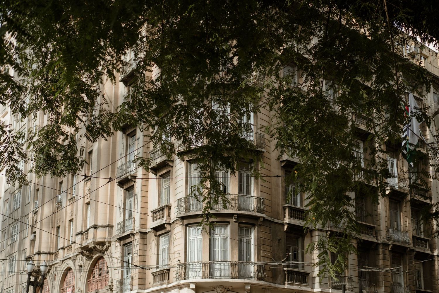 Historic apartment building facade with ornate architectural details and tree branches.