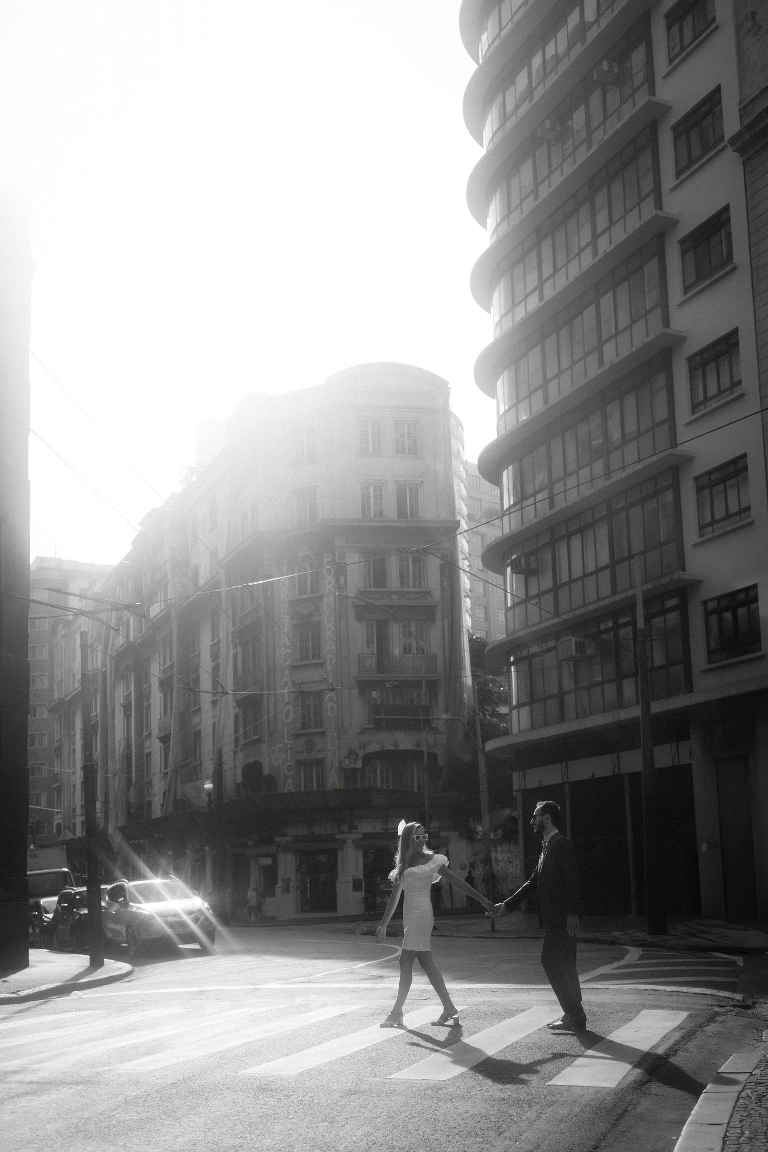 Backlit silhouettes walking in an urban street with sunlight streaming between buildings.