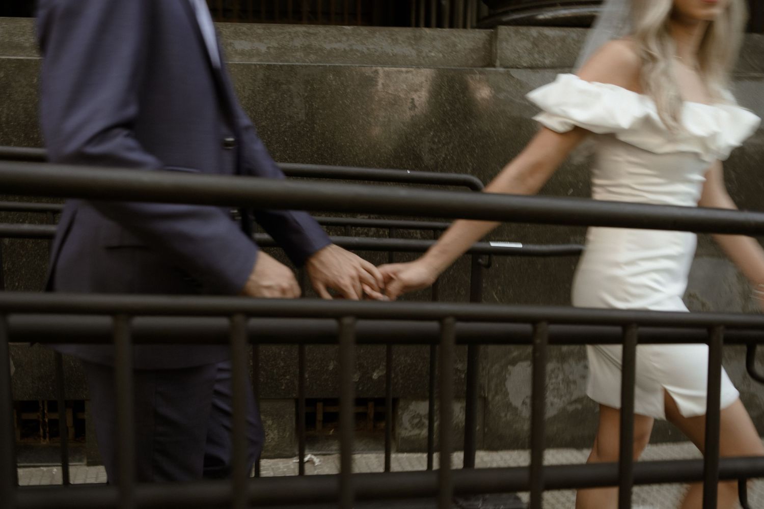 Close-up of a couple holding hands while standing on stairs, with focus on their interlocked fingers.
