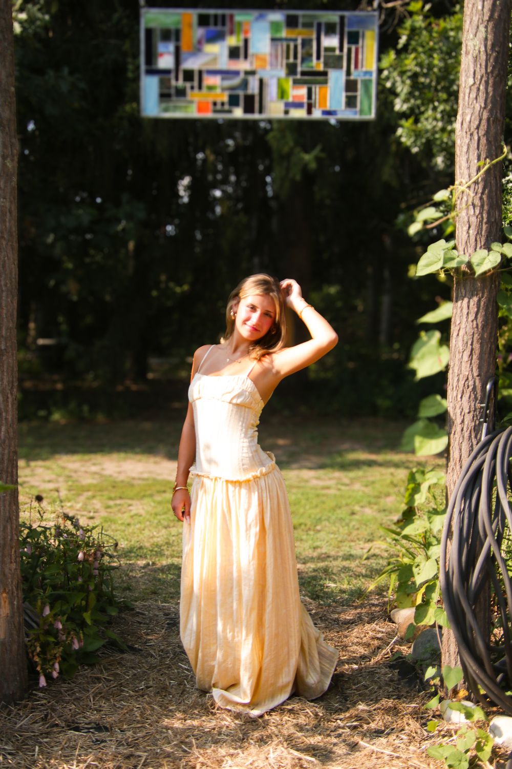 Summer outdoor photoshoot with decorative stained glass artwork hanging among trees.