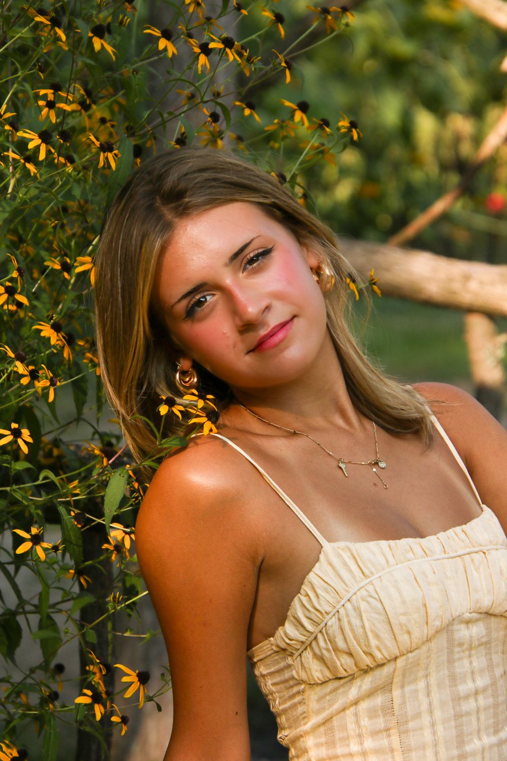 Golden hour portrait amid blooming yellow black-eyed susan flowers in a garden setting.
