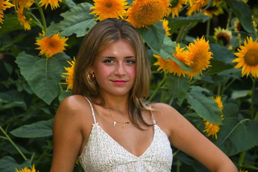 A white sundress against a vibrant background of blooming sunflowers in a garden setting.