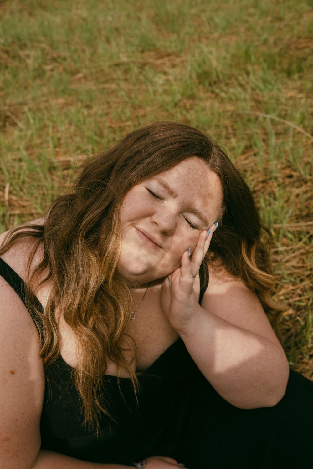 Candid portrait captured in warm sunlight against a natural outdoor backdrop.