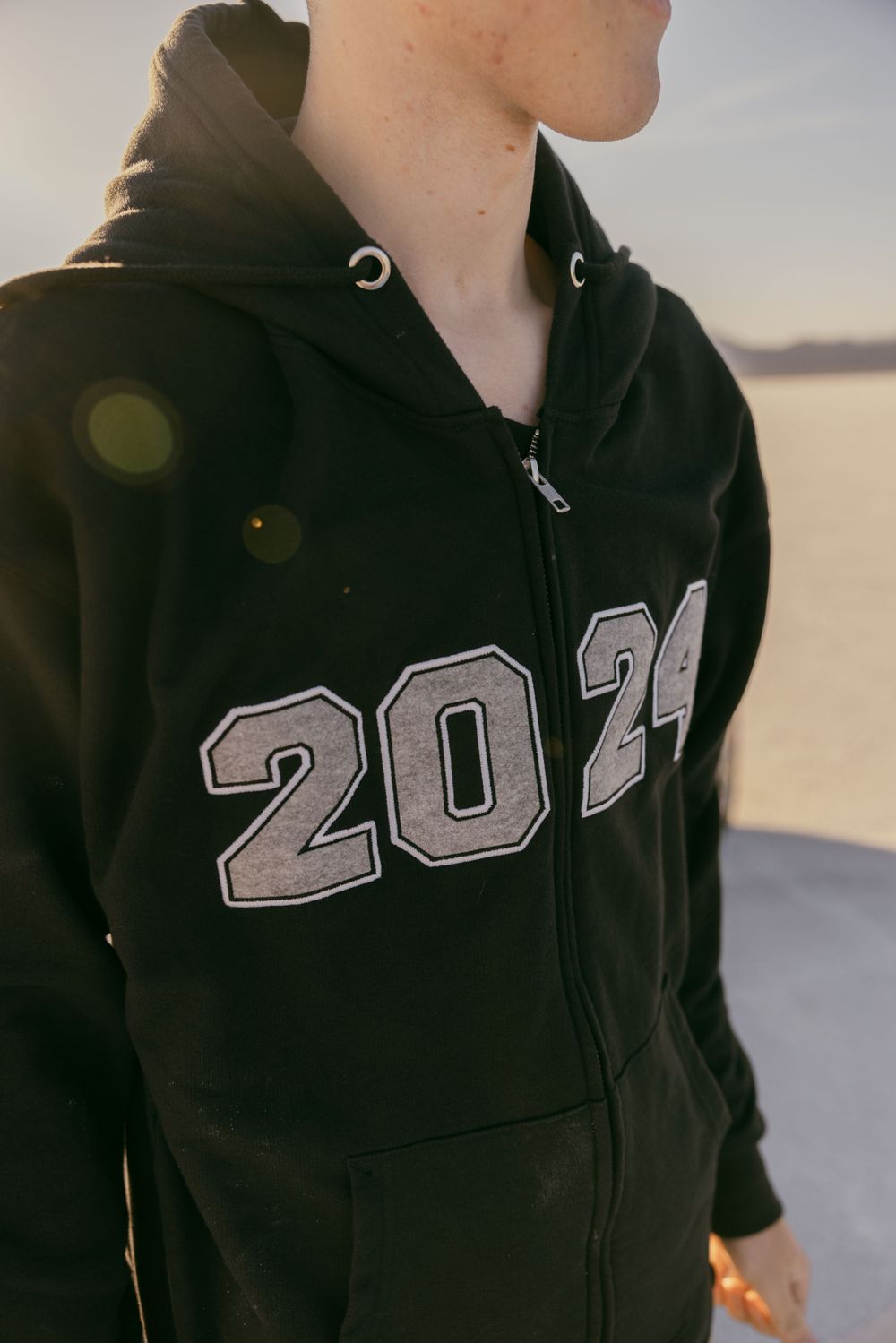 Close-up detail of black zip-up hoodie with 2029 numbers in varsity lettering style.