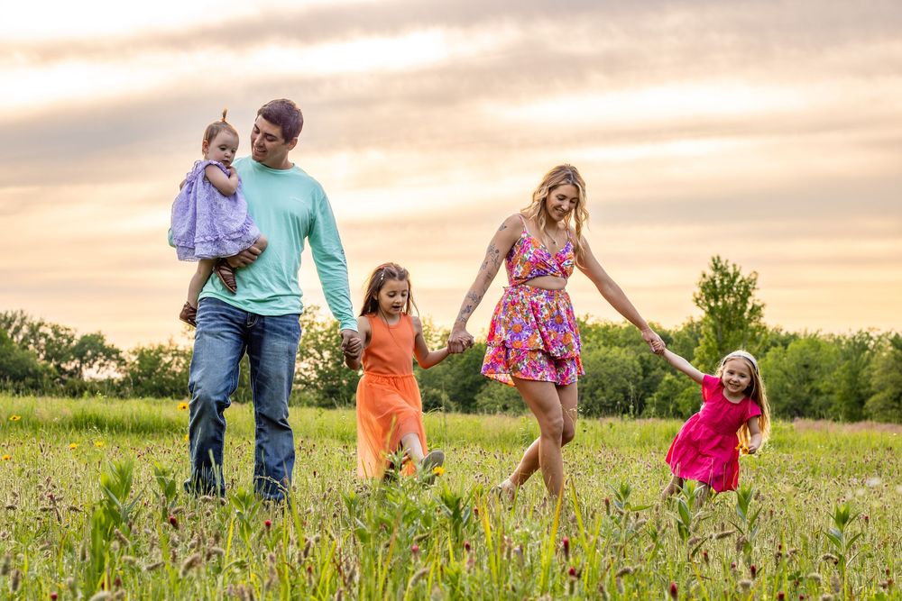 Family walking and playing together in a flower field during golden hour sunset lighting.