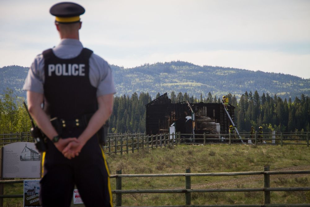 RCMP officer overlooking a rural farm property with forested hills in background.