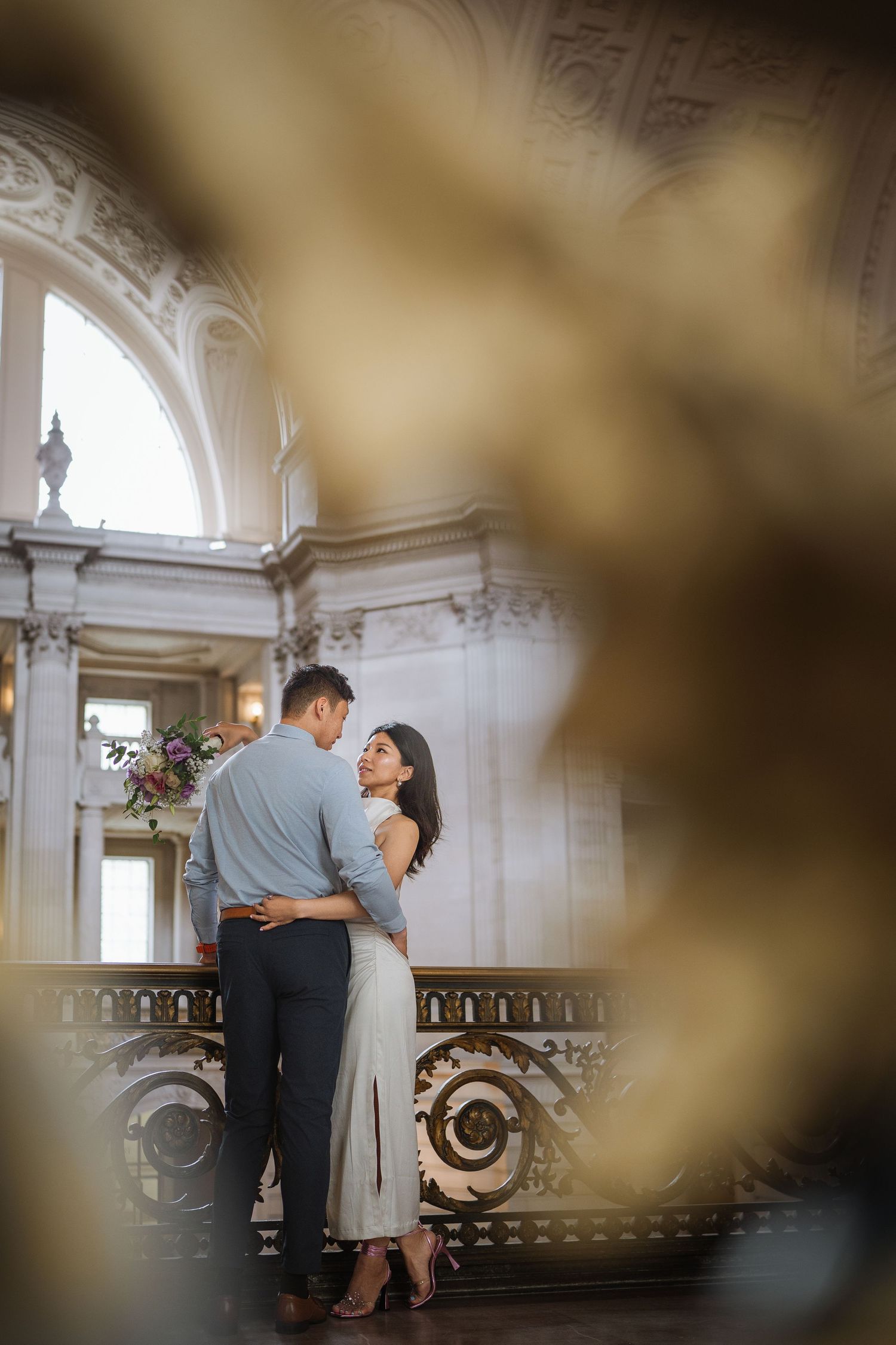 Intimate moment captured in grand historic building with decorative baroque railings and arches.
