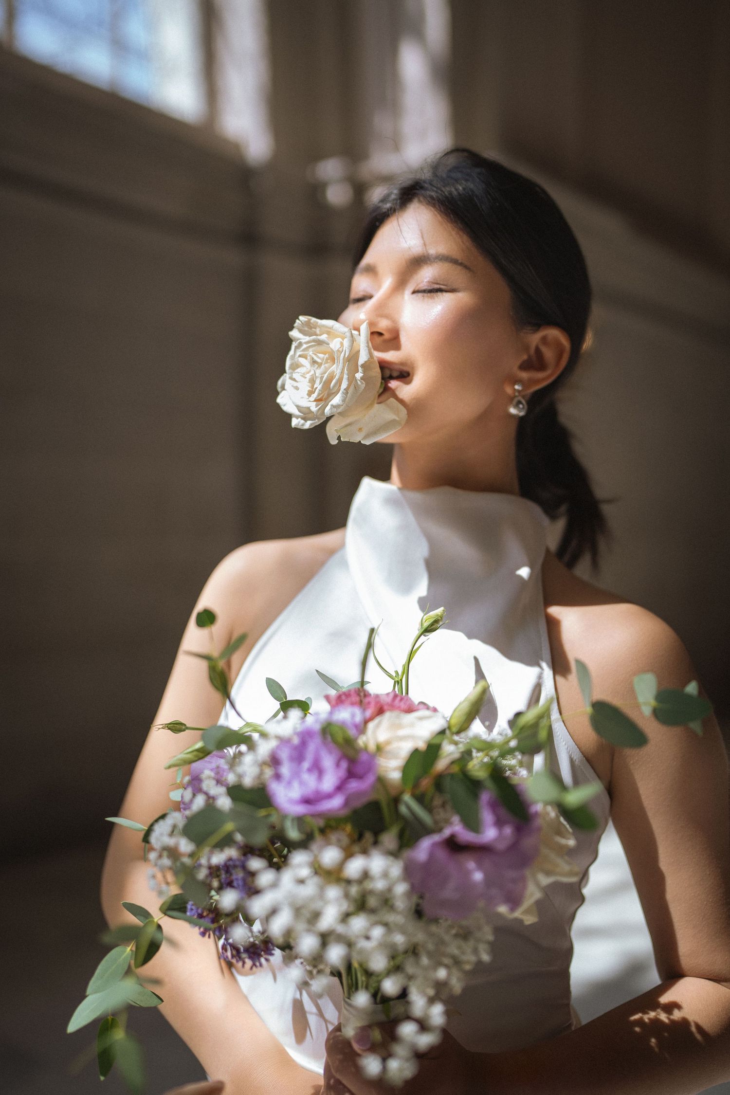 Close-up portrait with delicate purple and white bouquet in natural window lighting.