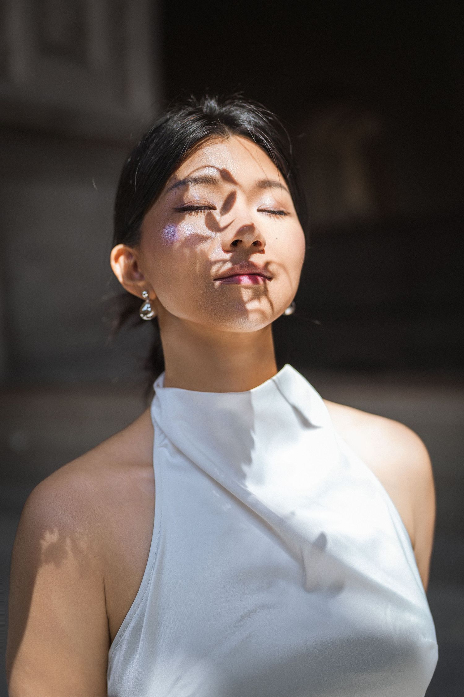 Artistic bridal portrait with dramatic shadows and white high-neck dress.