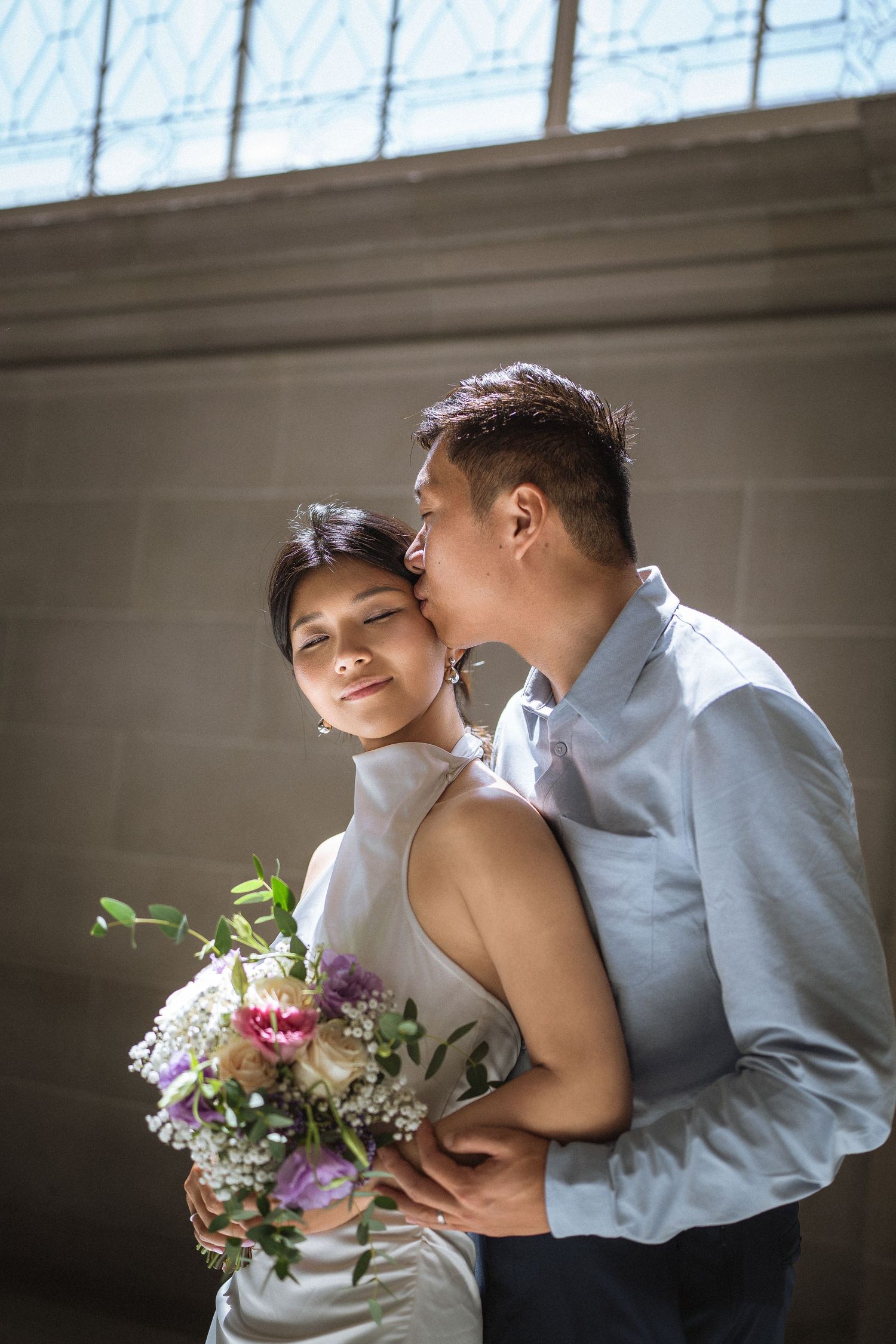 Intimate wedding portraits under natural light with purple floral bouquet.
