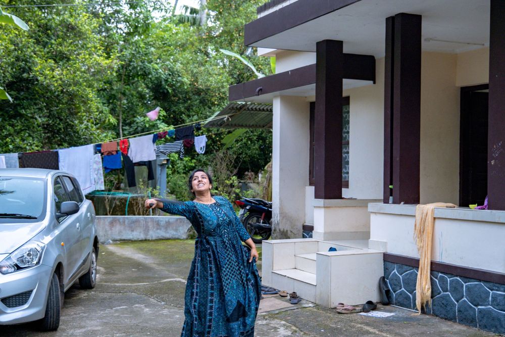 People in blue traditional dress releasing white doves into the air near a house.