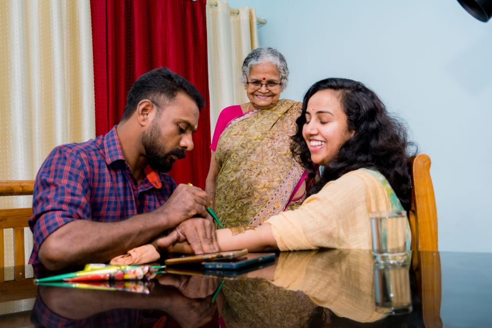 People at a table enjoying a traditional mehndi application ceremony with intricate henna designs.