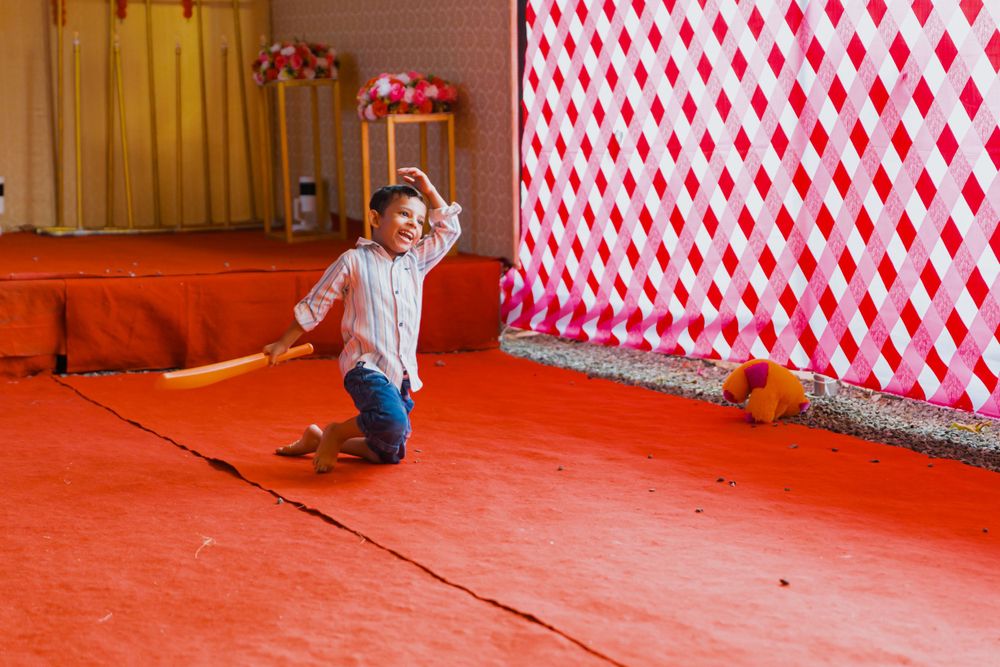 Child playing and jumping on red carpet at wedding venue with decorative backdrop.