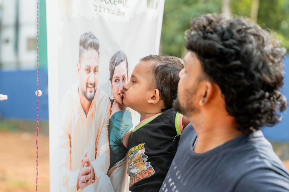 Young child kissing a welcome banner at an outdoor event.