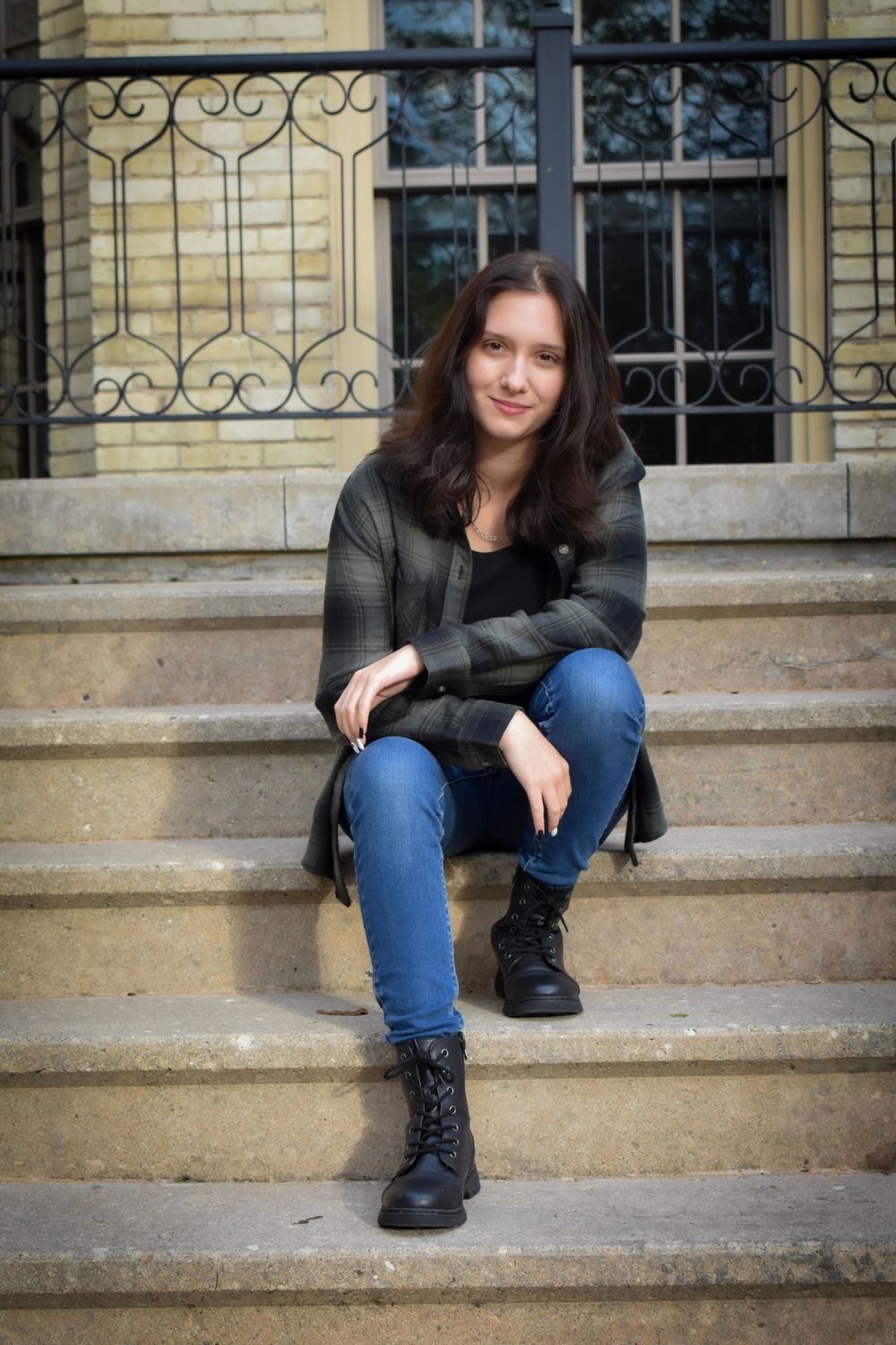 Casual portrait on stone steps with ornate iron railing in background.