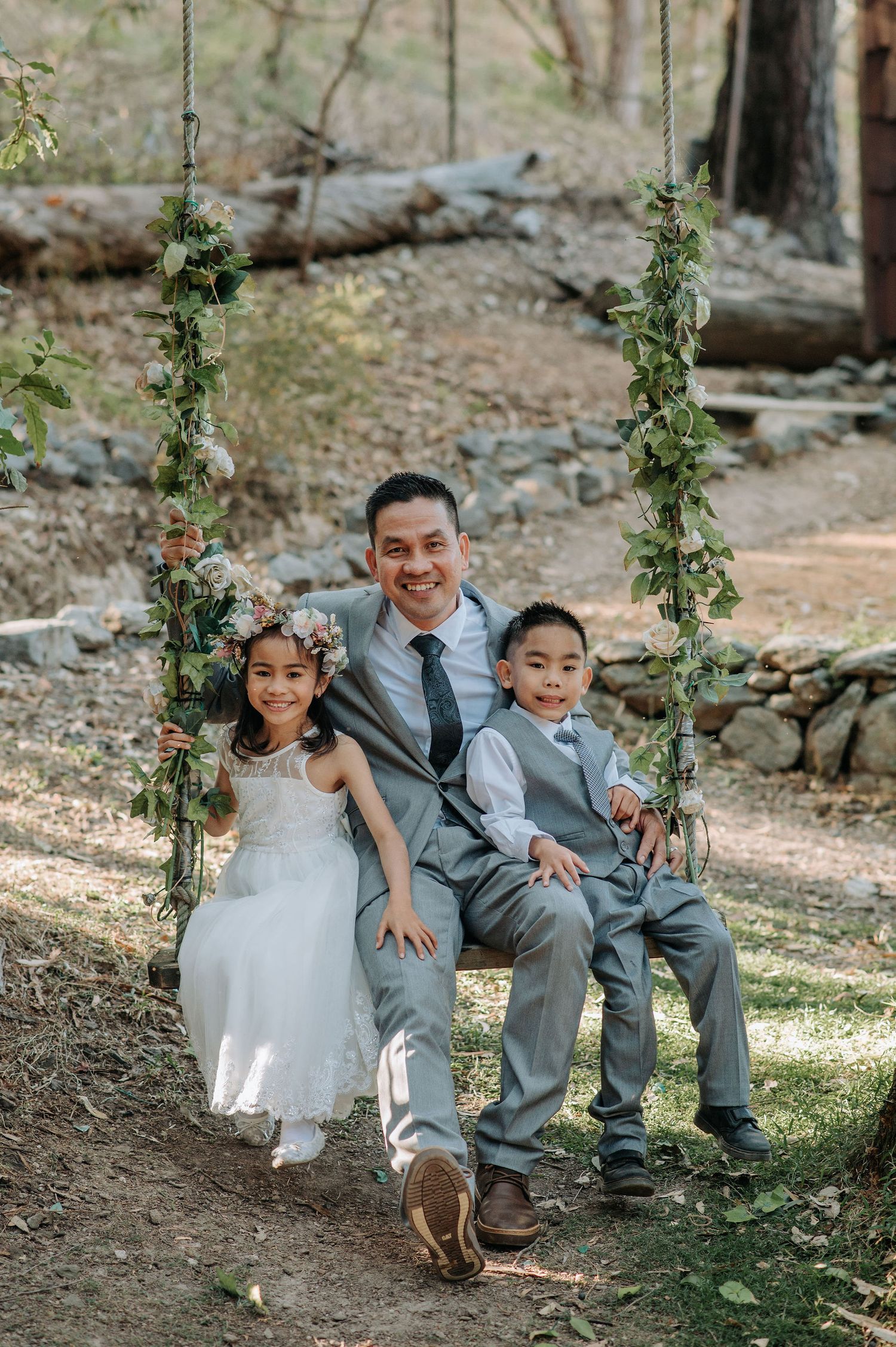 A joyful moment on a flower-adorned swing in a rustic outdoor wedding setting.