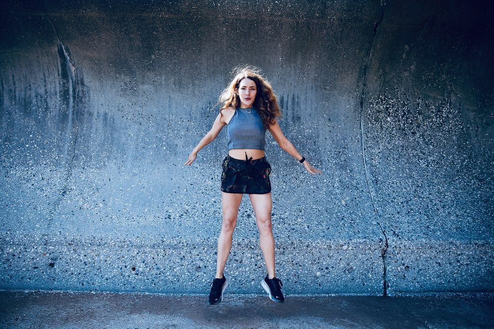 Artistic sequence of jumping silhouettes against a textured blue wall background.