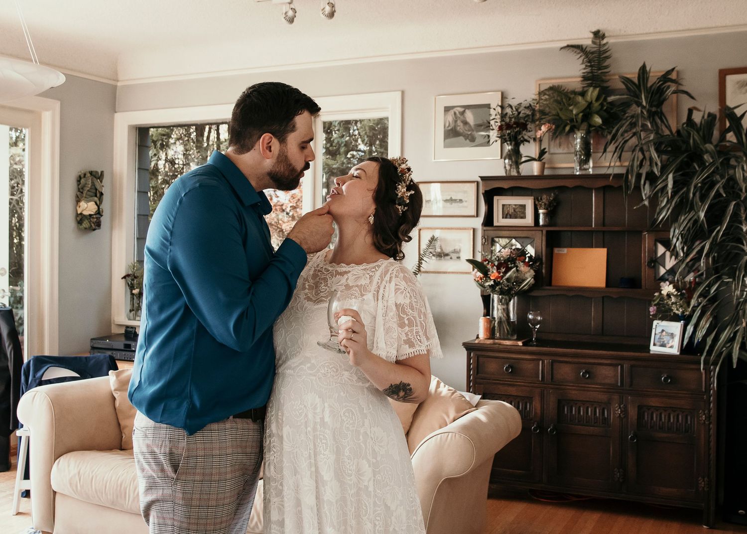 Romantic couple sharing intimate moment in cozy living room with vintage furniture and indoor plants.