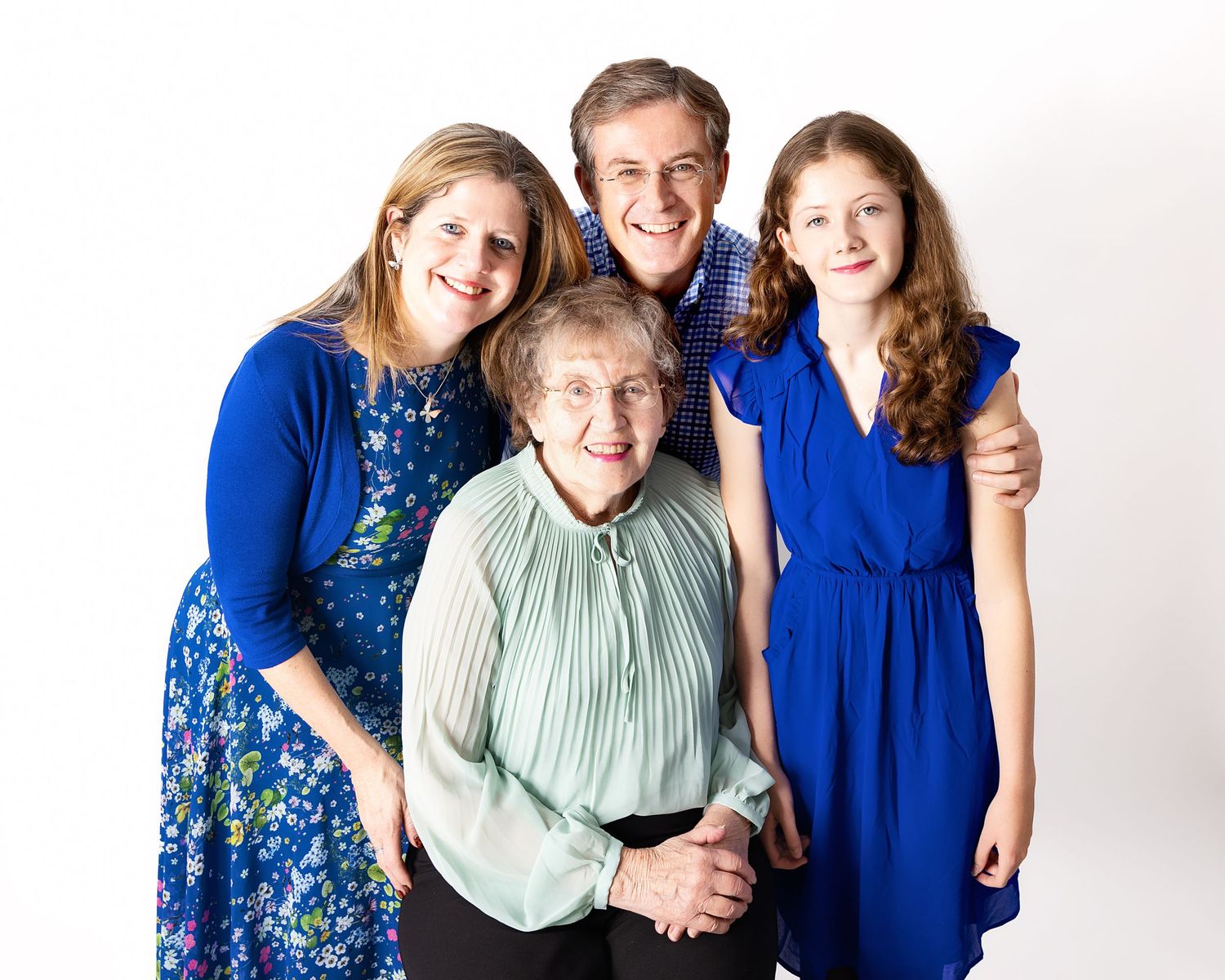A family group wearing coordinating blue outfits poses together against a white studio backdrop.