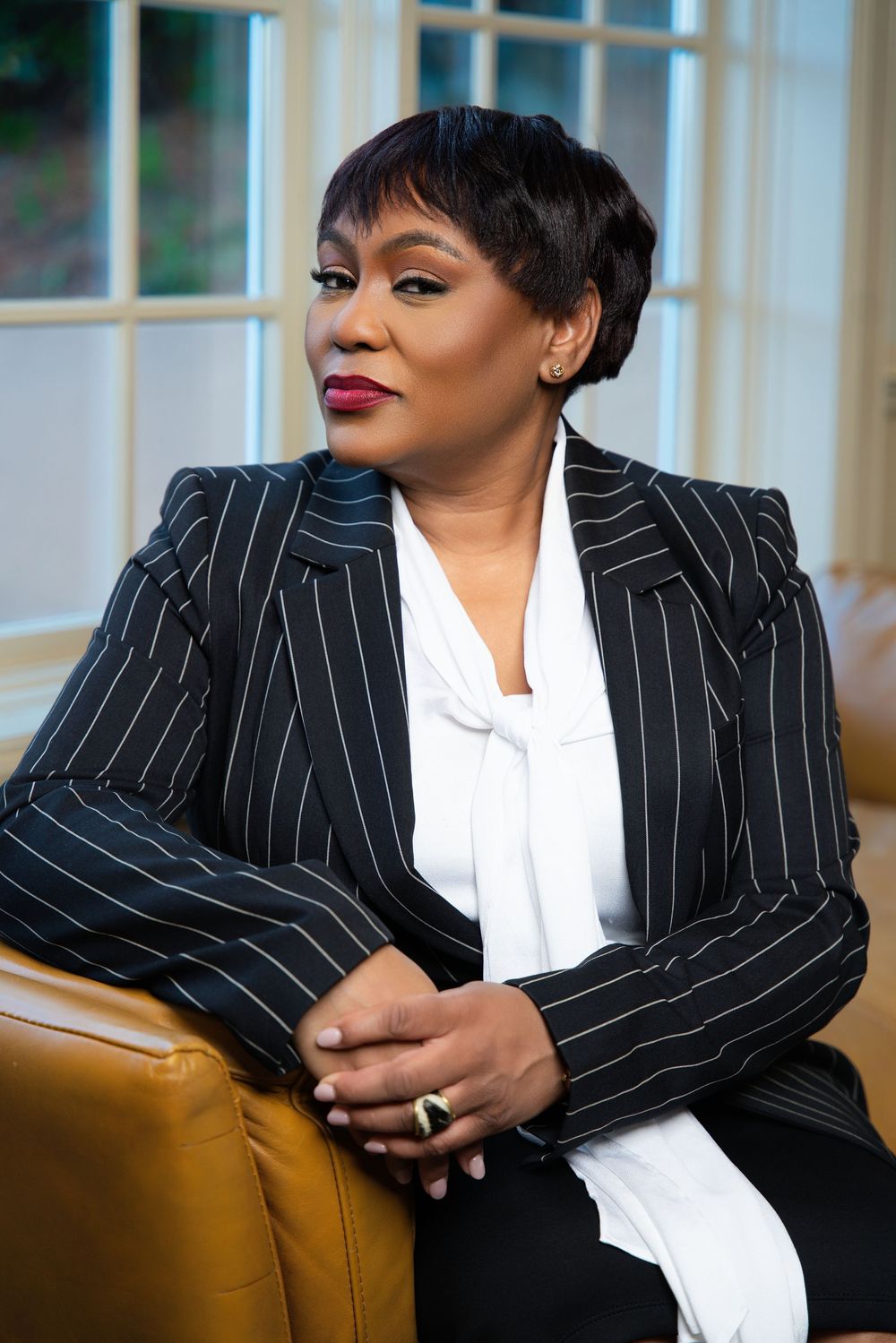 Professional portrait series showing a black pinstripe blazer and white blouse against a golden chair in elegant lighting.