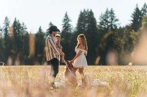 People relaxing in a sunlit meadow with evergreen trees in the background.