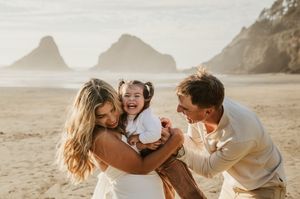 Playful moment captured on a scenic beach with rocky cliffs in the background.