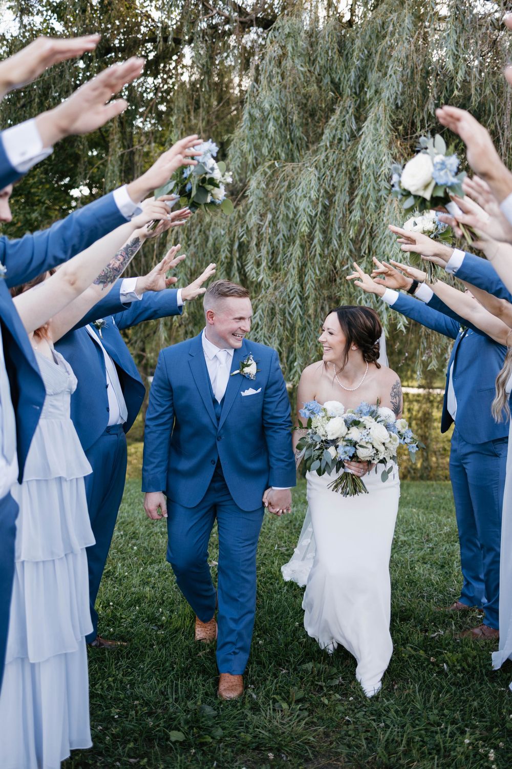 Bride and groom walking through a tunnel of their own bridal party at Willowbrook