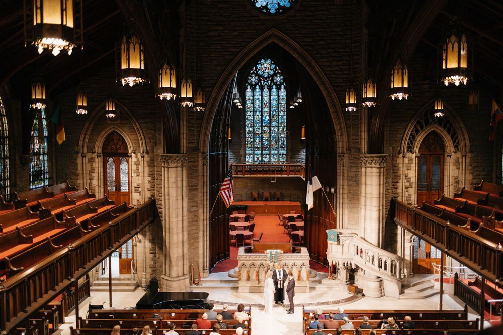 Wedding ceremony taking place inside a historic church with stained glass