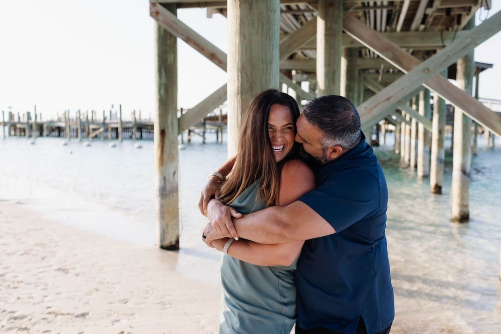 Happy couple hugging on the beach with calm sea behind them