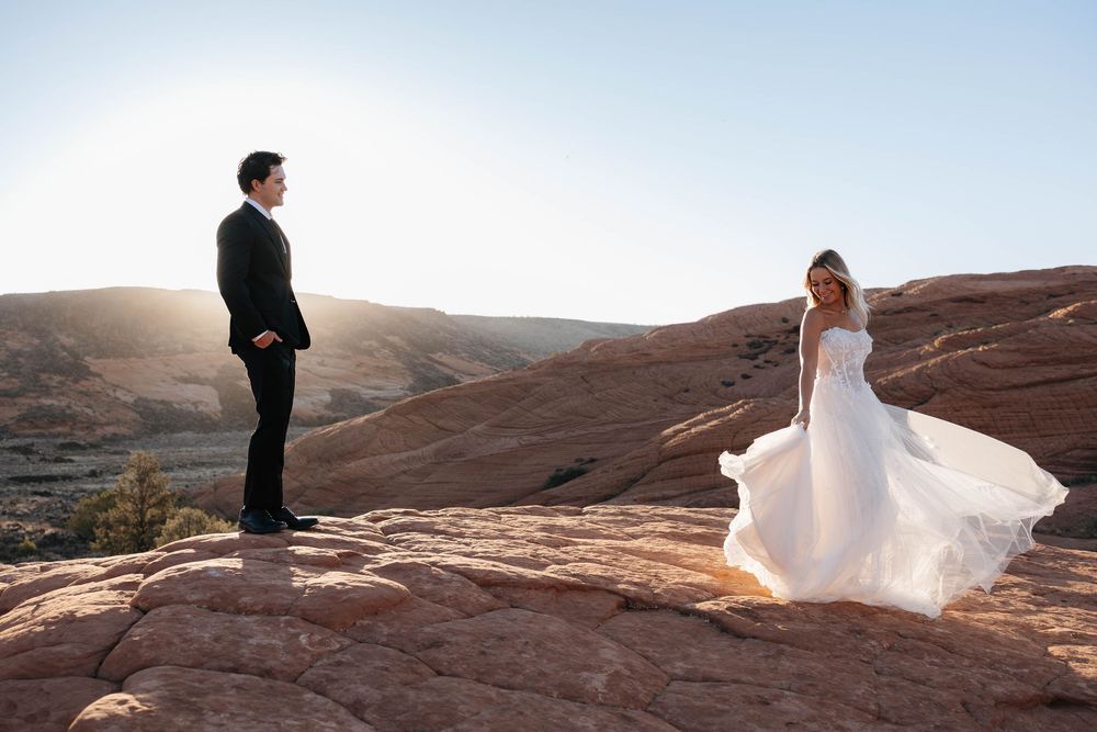 Wedding couple posing in Snow Canyon with red rock desert cliffs.