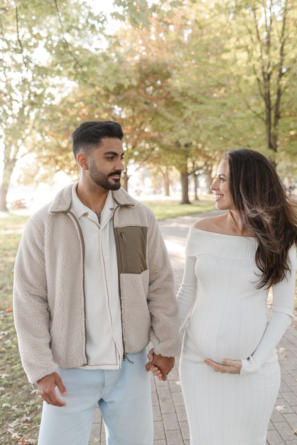 Toronto couple, looking at each other, at high park for a maternity photoshoot in the Fall. Captured by Jess GC Photography