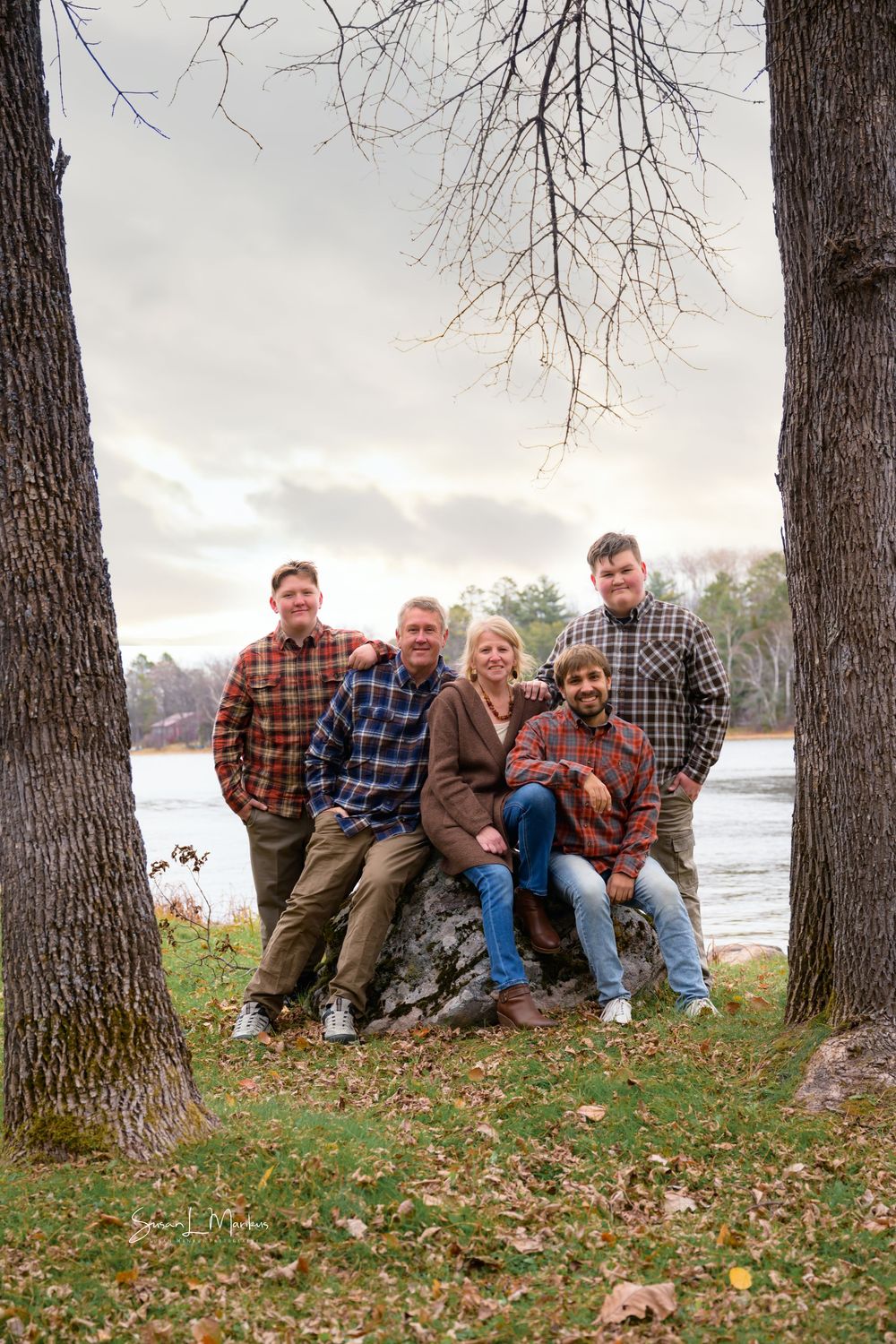Family of five on rock with lake in background in the fall