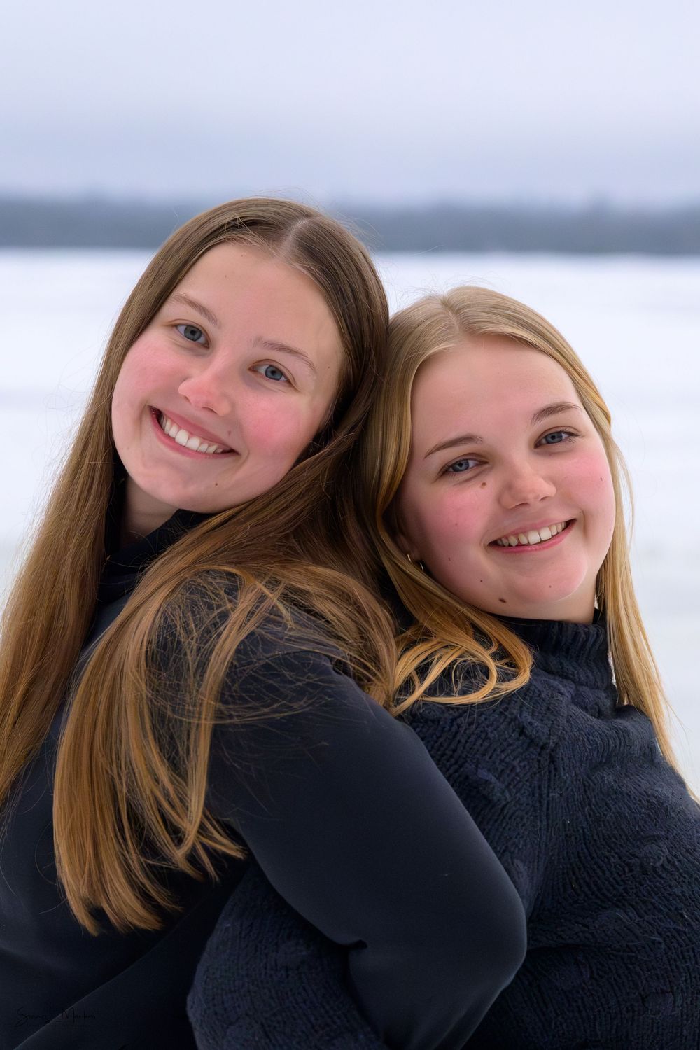 two young sisters smiling with lake background
