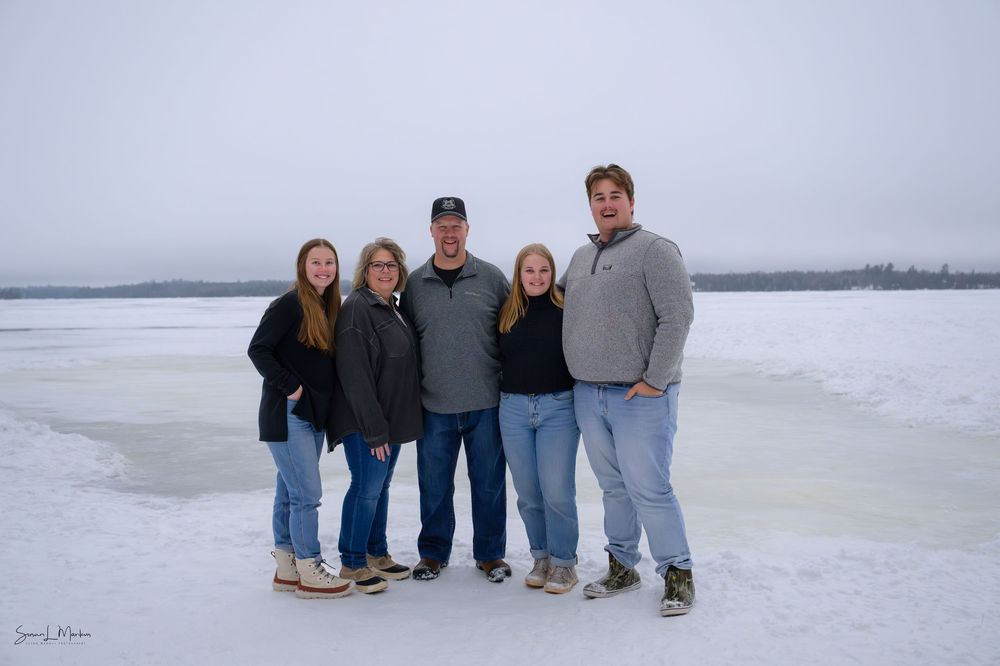 Family of five posing on lake in winter scene