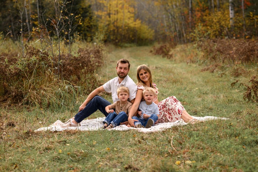 Young family of four on blanket in forest