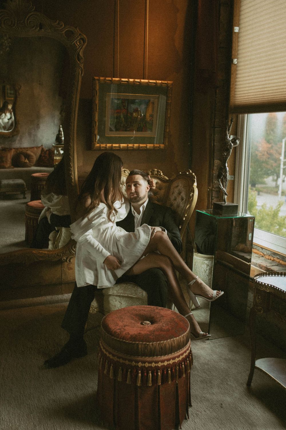 A couple sharing an intimate moment in a richly decorated vintage room with ornate furniture and warm lighting.