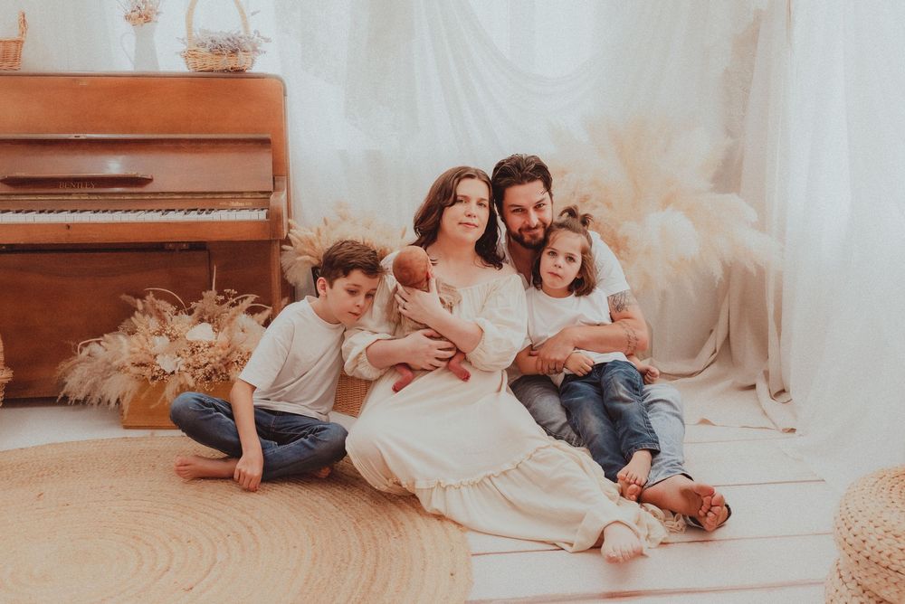 A series of intimate family moments captured on a white sofa against light neutral backgrounds in a flowing sequence.