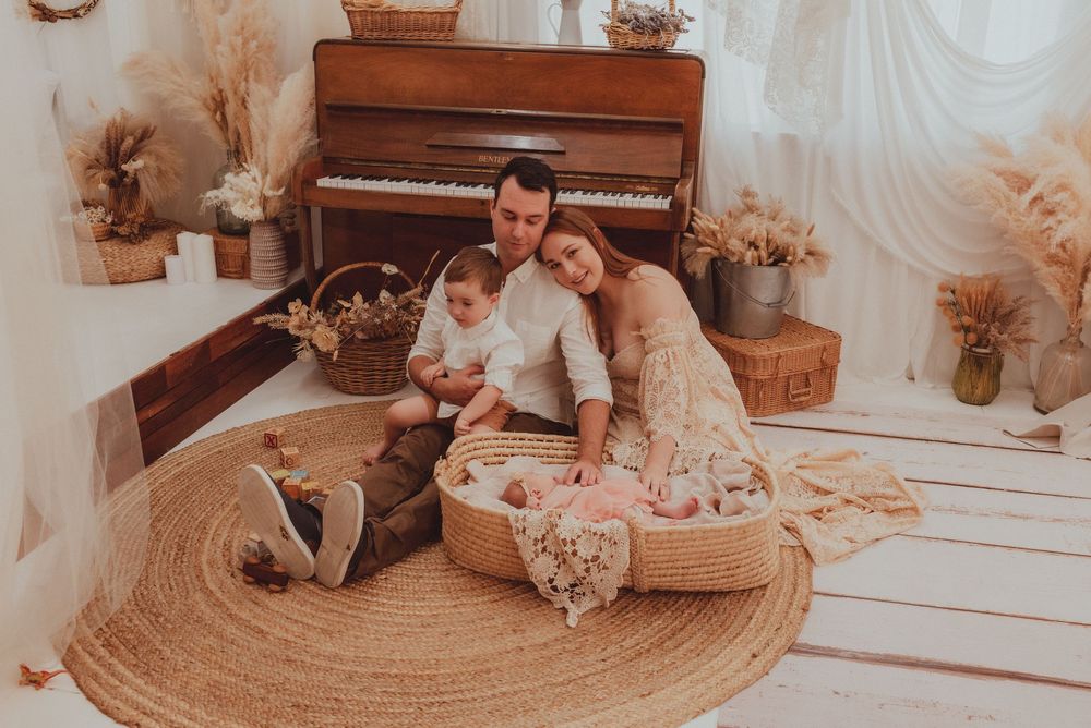 A person plays a wooden piano while surrounded by warm-toned decor and floral arrangements.