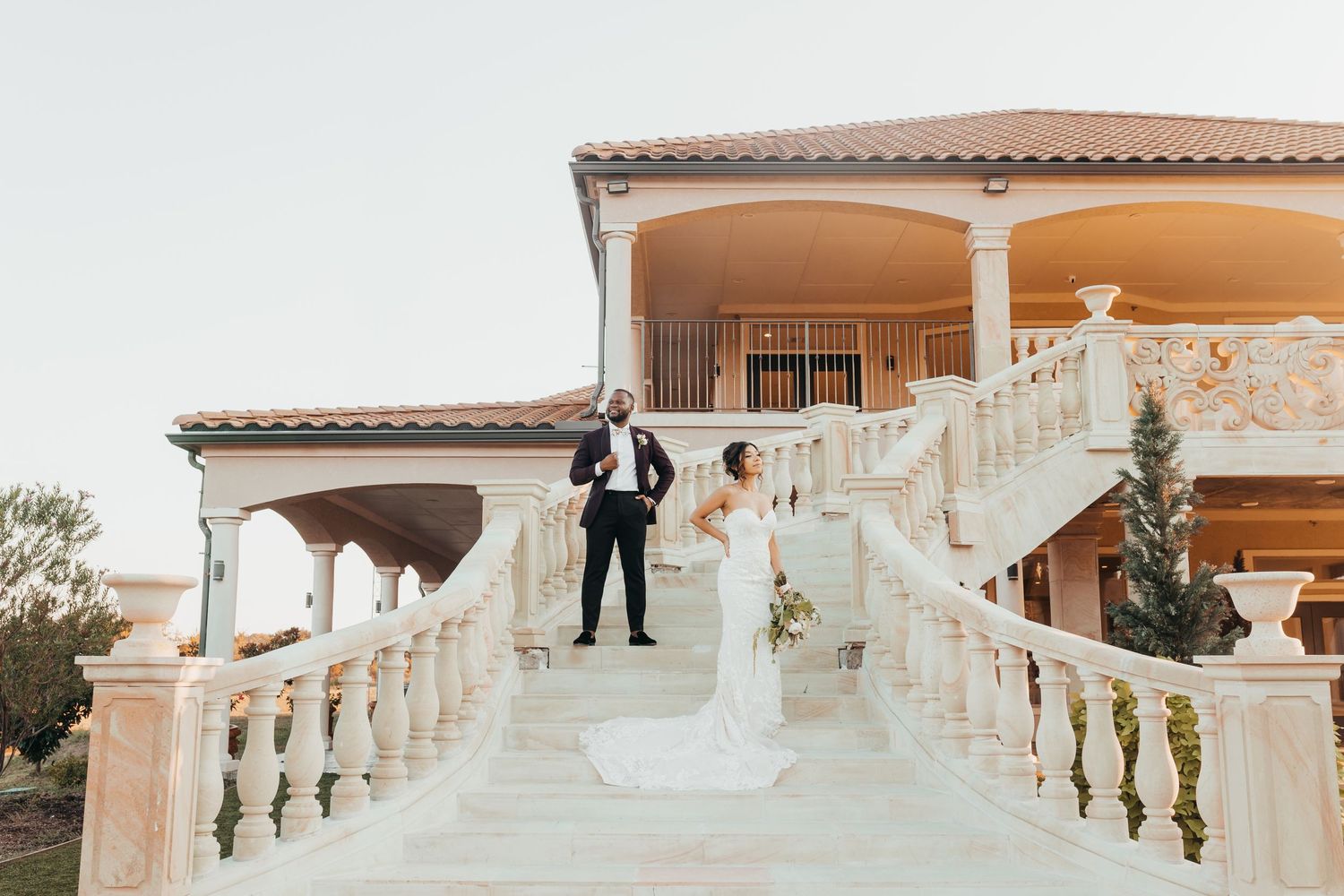 Elegant wedding photo on grand white marble staircase at Mediterranean-style villa.