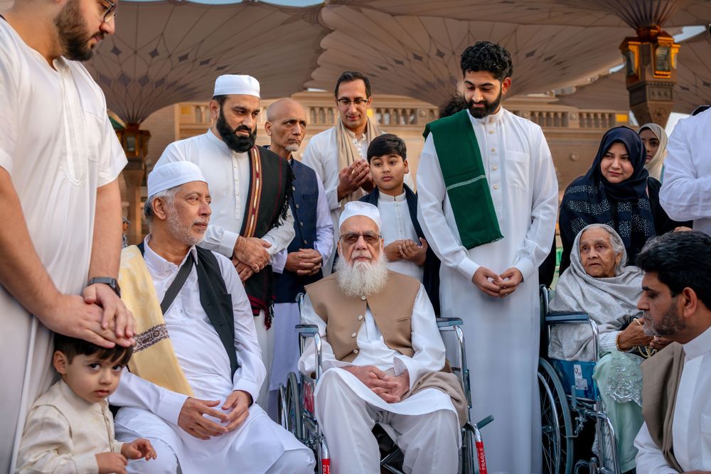 A group of people in traditional Islamic dress gather outdoors during a religious or cultural gathering.