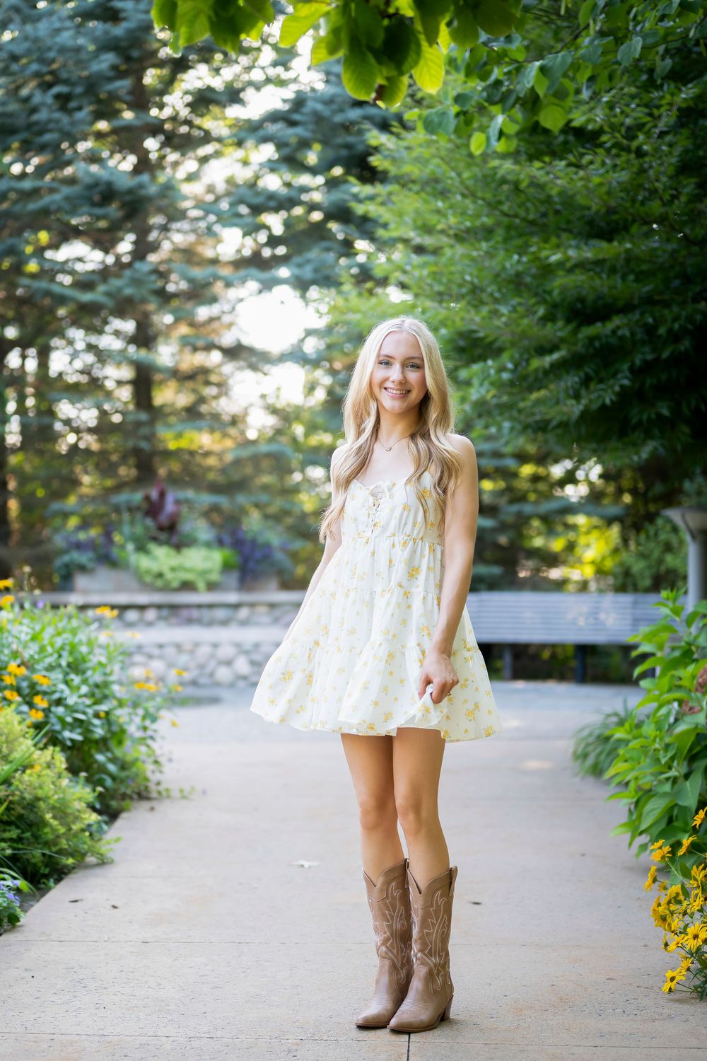 Brown cowboy boots paired with a white dress on a garden walkway.