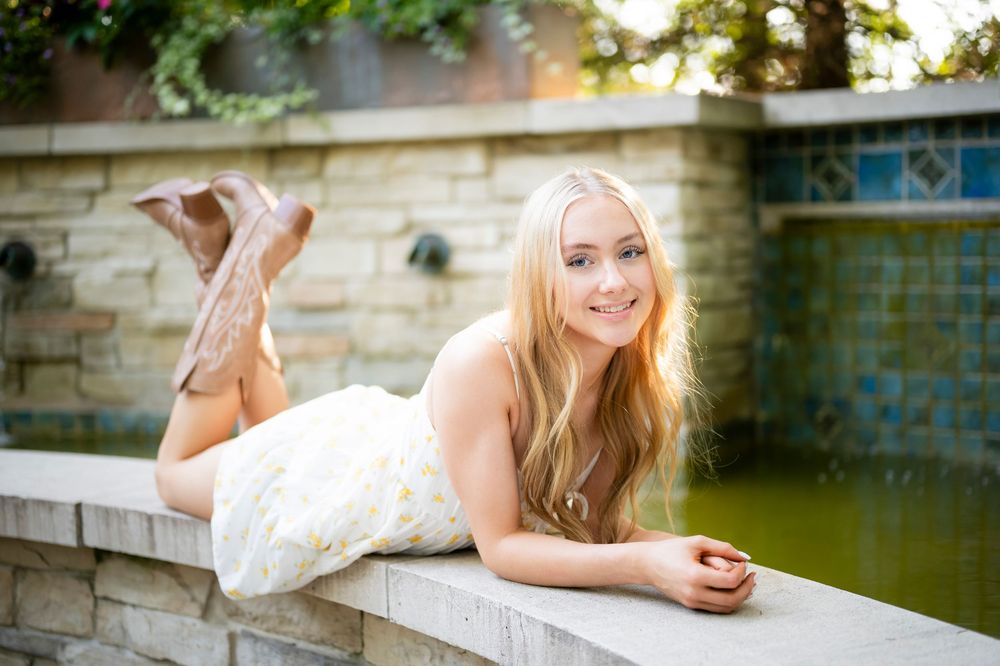 Casual summer portrait on a stone ledge near a reflecting pool.
