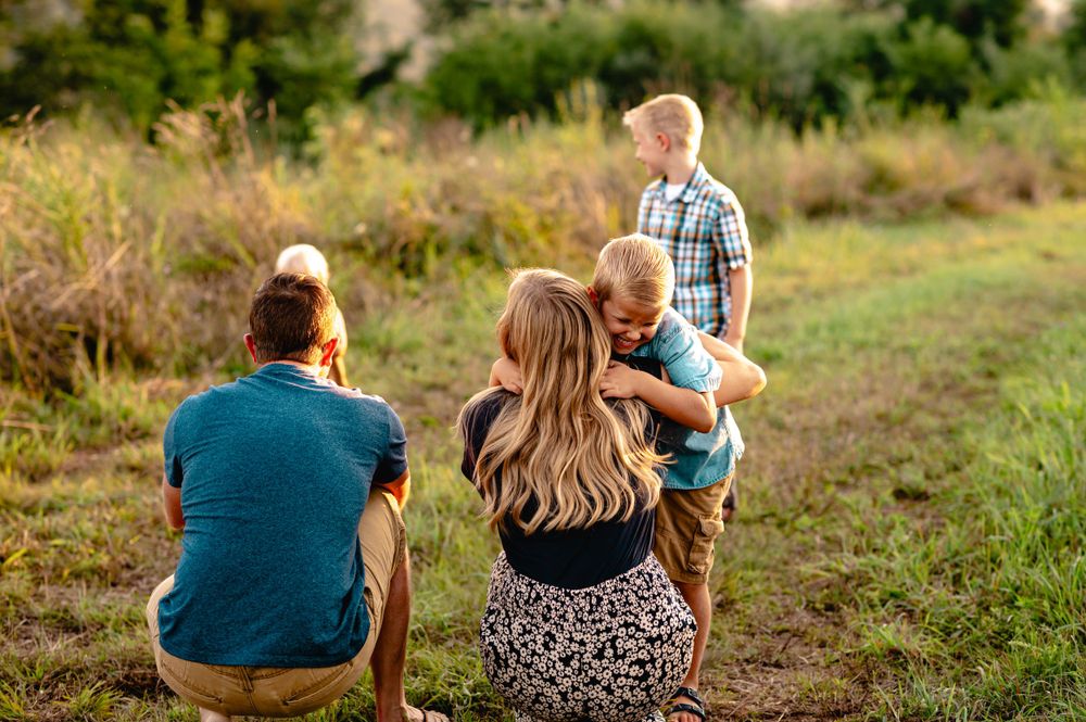 A family enjoying time together while sitting in a grassy field on a warm autumn day.