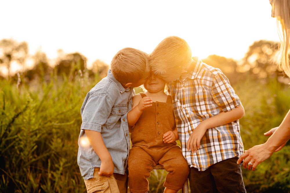 A loving family shares a tender moment together in a sunlit field during golden hour.