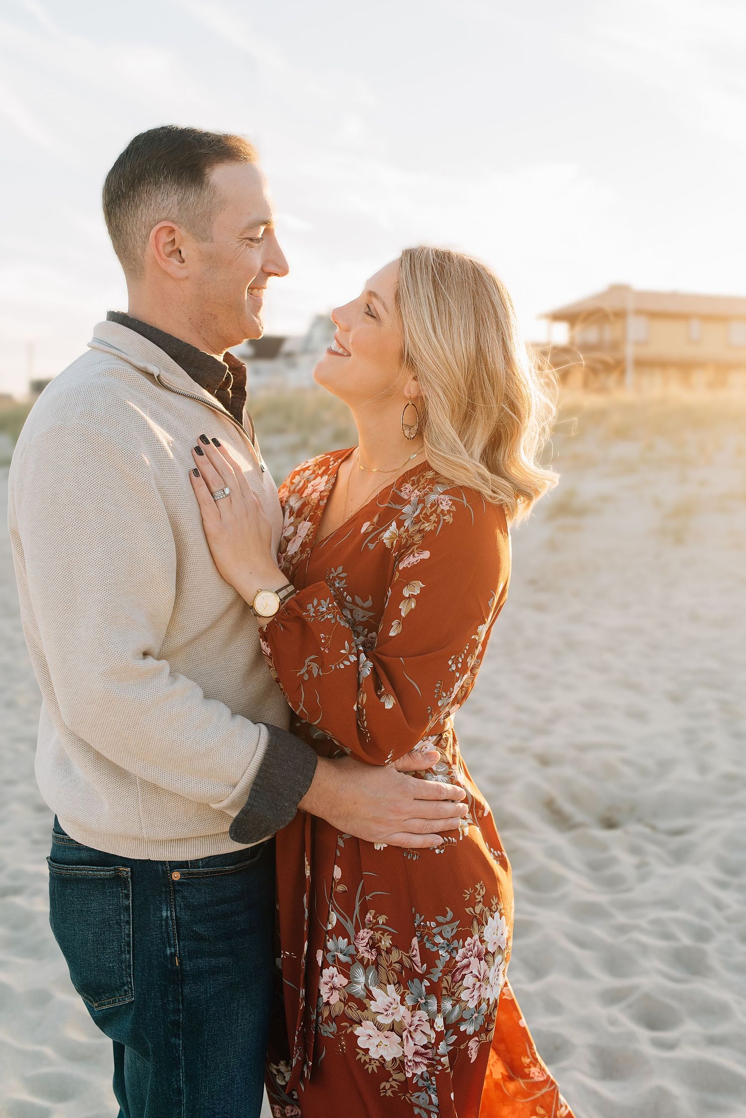 A husband and wife hold one another with the sun setting behind them on the Manasquan beach.