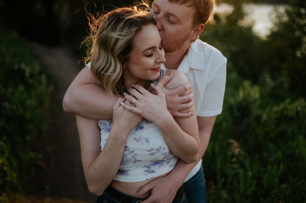 A romantic outdoor engagement photoshoot featuring a couple embracing against a natural backdrop during golden hour.