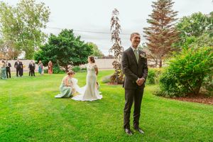 People gather outdoors with beautiful coastal scenery and evergreen trees in the background on a bright summer day.